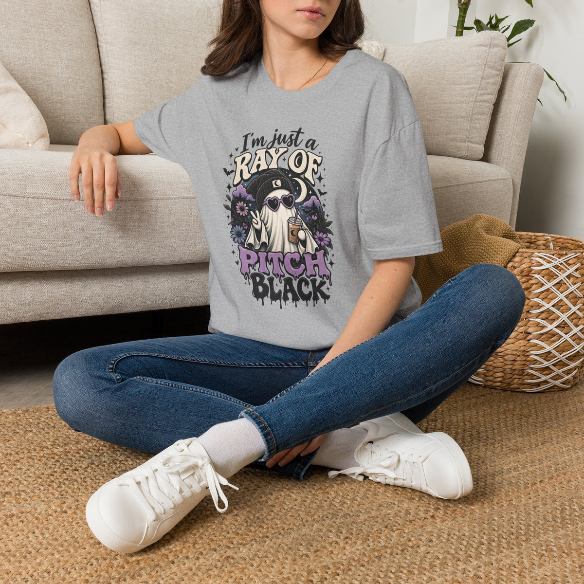 Person wearing a gray t-shirt with a printed design sitting on a couch.