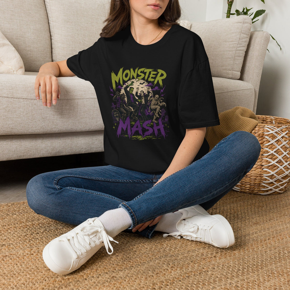 Person wearing a black t-shirt with a tree design, sitting on the floor in a living room.