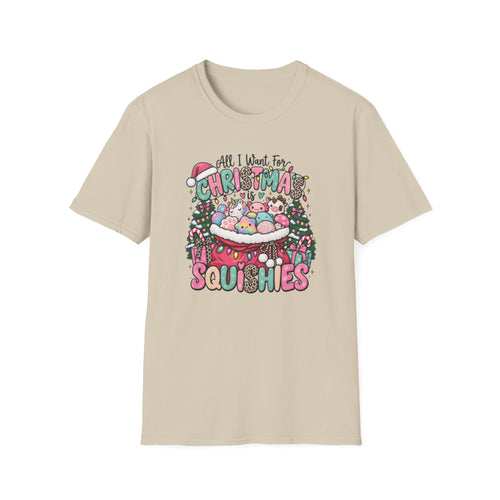 A beige crewneck t-shirt featuring a colorful Christmas-themed graphic on the chest with the text 'All I Want For Christmas is SQUISHIES' and cute pastel squishy characters.