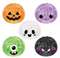 Five round, pumpkin-shaped glittery stress balls with cute cartoon faces, shown in orange jack-o'-lantern, purple smiling face, white ghost, green one-eye monster, and black vampire designs on a white background.