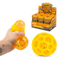 Yellow honeybee fusion quish ball toy shown being squeezed in a hand, a large hollow honeybee-shaped ball, and a retail display box labeled 'Honeybee Fusion Quish Ball' on a white background.