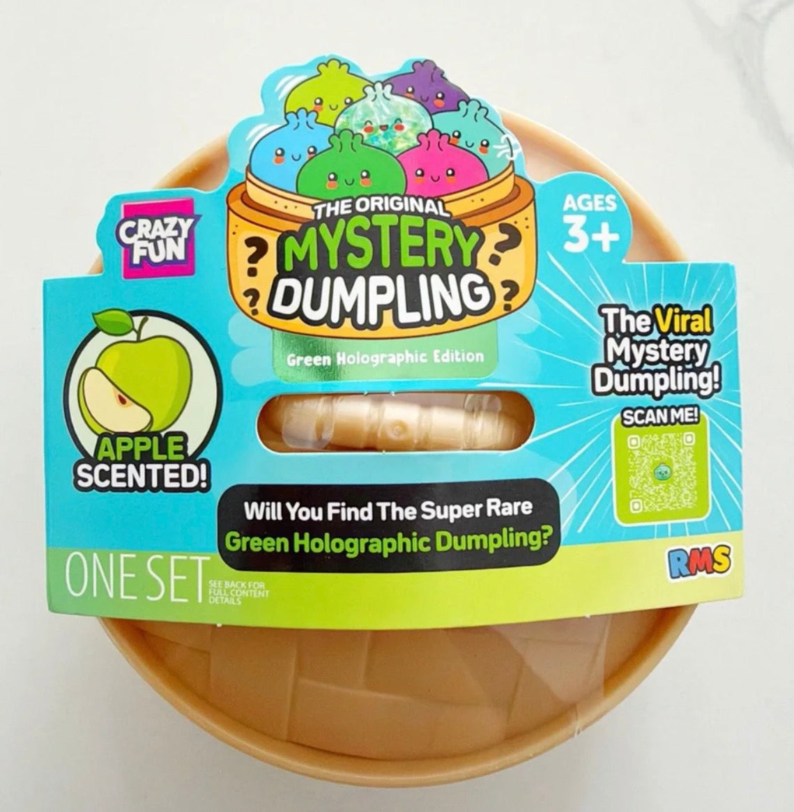 The Original Mystery Dumpling Green Holographic Edition by Crazy Fun, in an apple-scented one-set package with a visible holographic dumpling inside a plastic container, shown on a white background.
