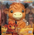 Highland Cow toy in its original retail packaging, featuring a large orange-brown plush cow with black horns and a cream-colored snout, alongside a smaller cartoon Highland Cow character on the front of the box.