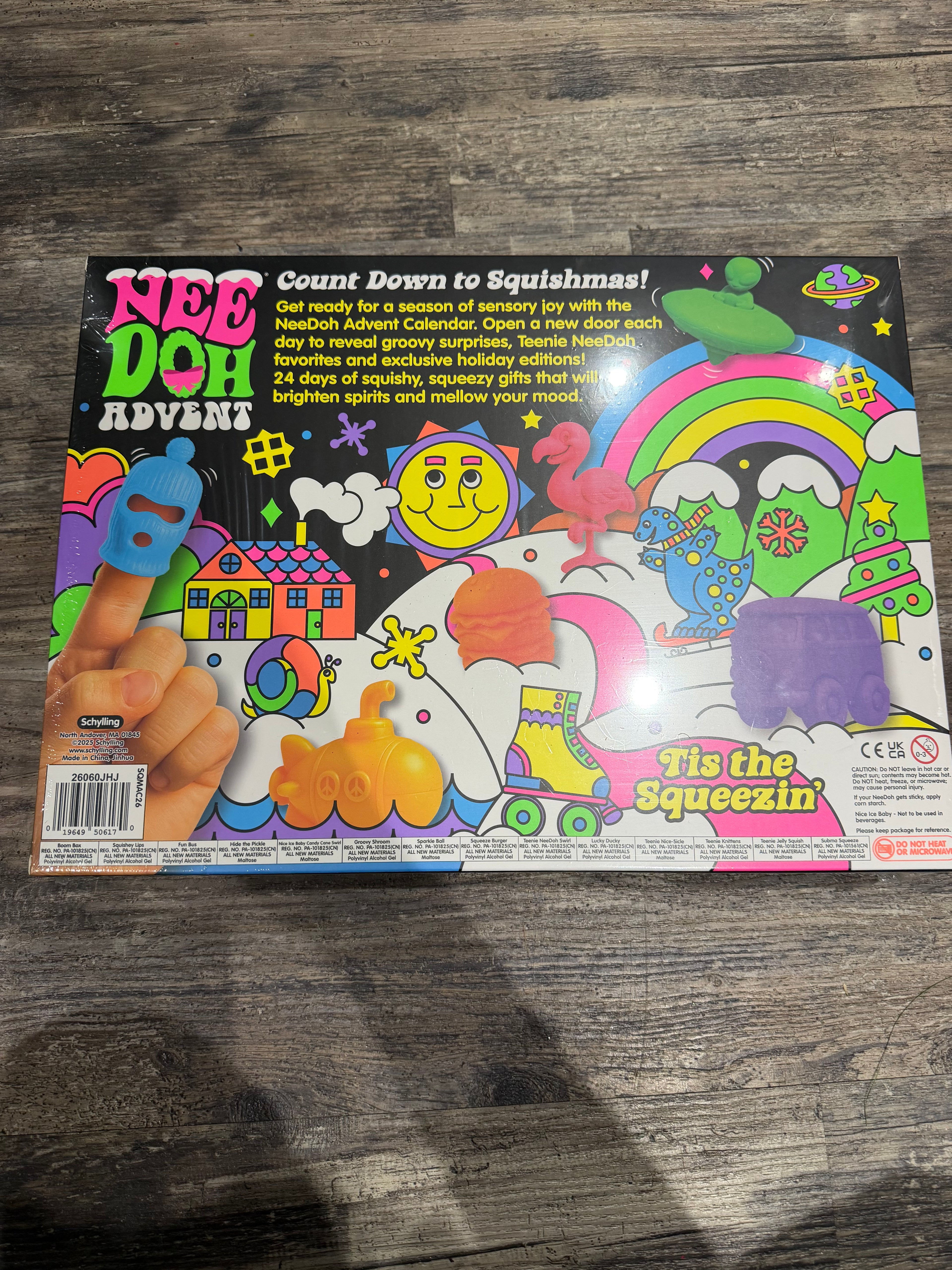 Nee Doh Advent 'Tie the Squeezin'' toy box shown from the back, featuring a colorful illustrated design with a hand pressing a blue squishy, set on a dark wood floor.
