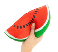 Large red with black seed watermelon, green crust with white line separating. Squishy toy being squished by a hand. 