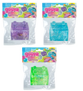 Three packaged squishy blocks from Craziest Toys, each in a clear plastic bag with a colorful header card. The packages show purple glitter, bright blue glitter, and neon green glitter squishy toys.