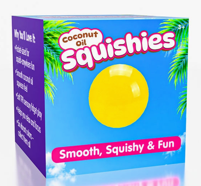 A boxed product labeled 'Coconut Oil Squishies' with a bright blue front panel, purple side panel, palm tree graphics, and a large yellow oval representing a squishie. The box is photographed on a clean white background with a faint reflection below.