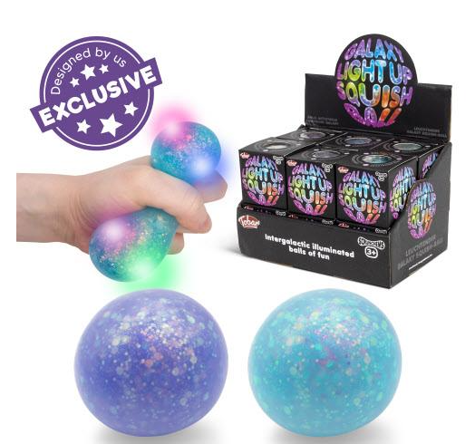 A hand squeezes a galaxy-themed light-up stress ball that glows with blue, green, and pink lights. Two more unlit balls are shown below, one purple and one blue, with a black display box of 'Galaxy Light Up Stress Balls' on the right.