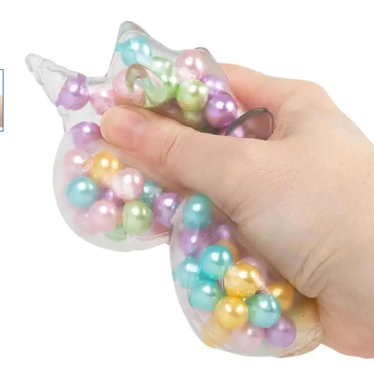 A hand squeezing a clear, star-shaped stress toy filled with pastel iridescent pearl-like beads in pink, blue, green, yellow, and purple, against a plain white background.