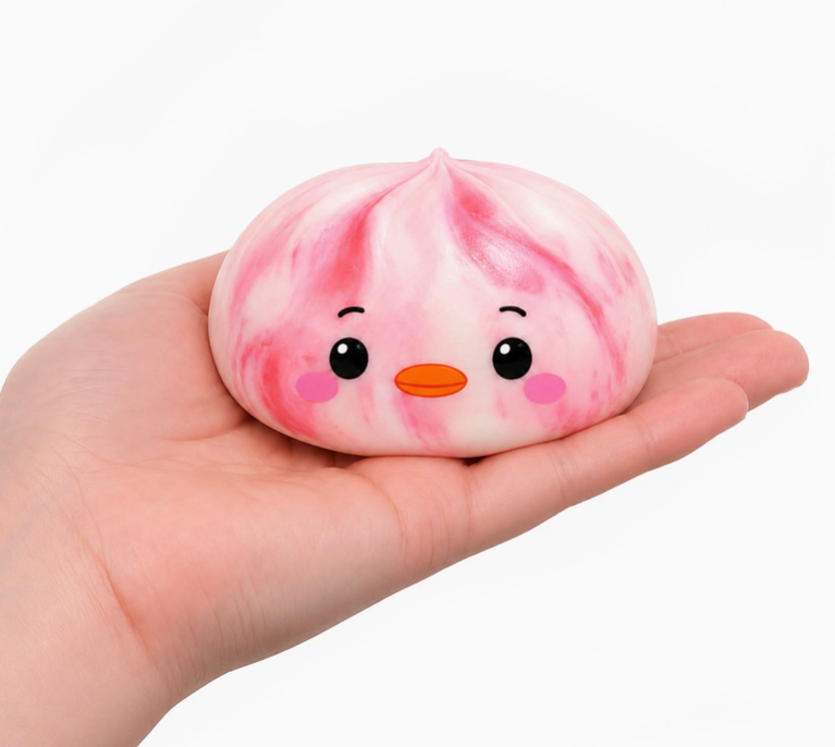 A cute, round pink and white marbled squishy toy with a cartoon face, resting on a person's hand against a clean white background.