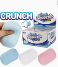 Squeeze Crunchy Sound squishy toys in light blue, white, and pink, shown with a hand squeezing a light blue toy and a box of Squeeze brand toys.