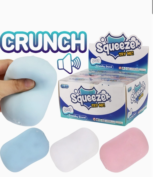 Squeeze Crunchy Sound squishy toys in light blue, white, and pink, shown with a hand squeezing a light blue toy and a box of Squeeze brand toys.