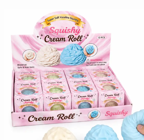 A pink display box labeled 'Squishy Cream Roll' containing 12 small individual boxes of the product, with three large cream and blue squishy rolls shown in the foreground on a white background.