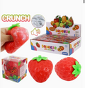 Strawberry-shaped ASMR squishy toys shown with a hand squeezing one, a retail display box, a smaller boxed unit, and two loose toys on a white background. The packaging and text mention 'CRUNCH' and 'squeeze soft stretchy'.