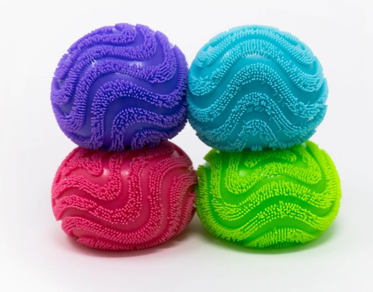 Four textured, ribbed exercise balls in purple, turquoise, pink, and lime green, stacked in a 2x2 grid on a white background.