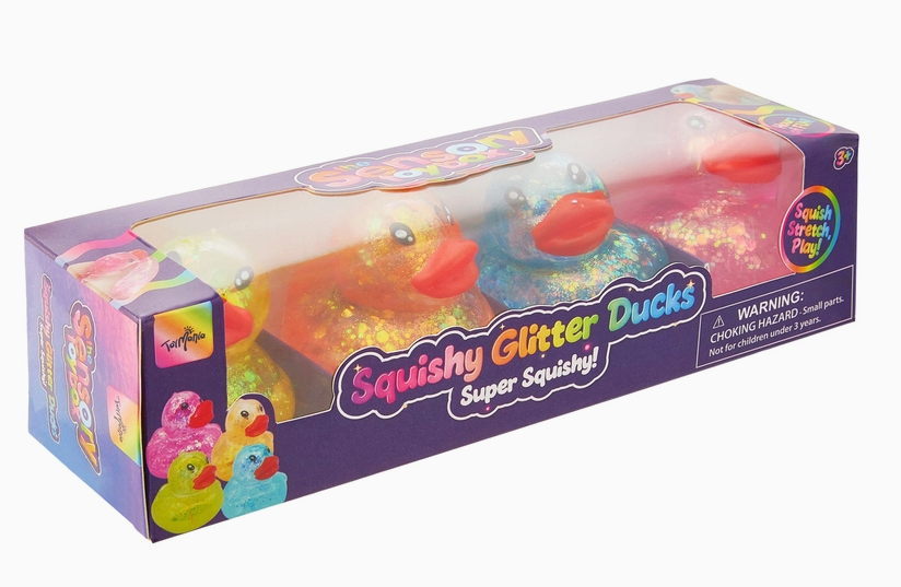 A boxed set of two glittery rubber duck toys visible through a clear plastic window on a white background. The packaging is purple with colorful graphics and the text 'Squishy Glitter Ducks Super Squishy!'.