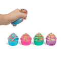 Hand squeezing a colorful squishy toy shaped like a cupcake with sprinkles on a white background.