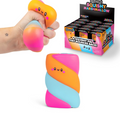A hand squeezes a pastel orange, pink, and light blue squishy toy with a smiling face, shown alongside a retail display box and another upright view of the same toy on a white background.
