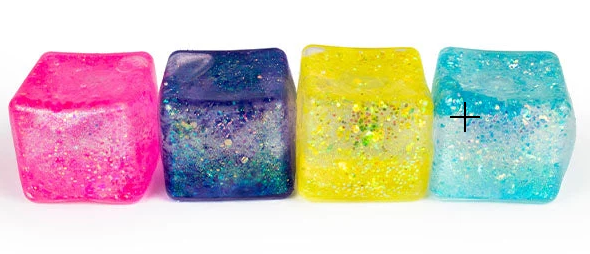 Four translucent glittery ice cube-shaped ornaments in pink, blue, yellow, and aqua, arranged in a row on a white background.